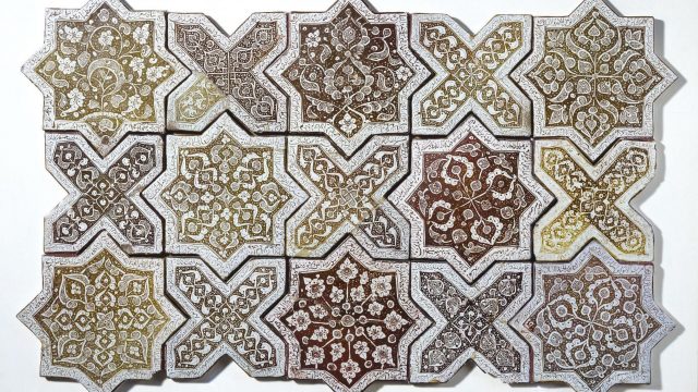 Panel of earthy-coloured Islamic tiles tessellated in a traditional geometric style