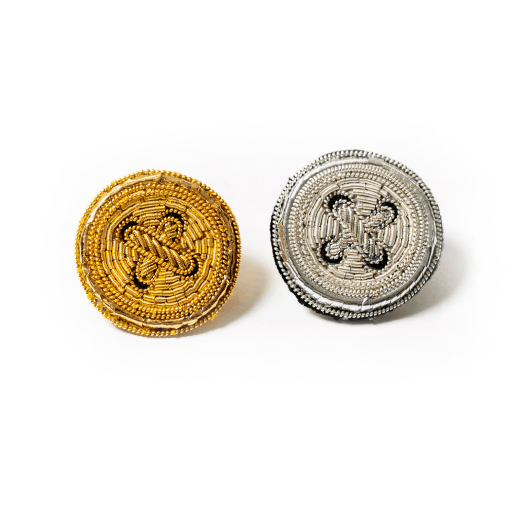 Two brooches embroidered with gold and silver thread in the shape of round buttons.