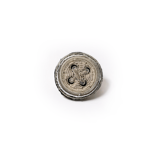 A brooch embroidered with silver thread in the shape of a round button.