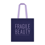 A blue tote bag with a purple text spelling 'Fragile Beauty' in capital letters and featuing a lilac handle.