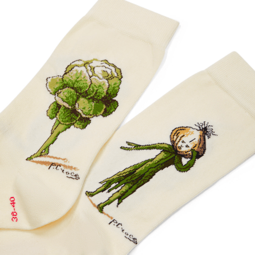 A detail image of a pair of off white socks with vegetable costume designs.