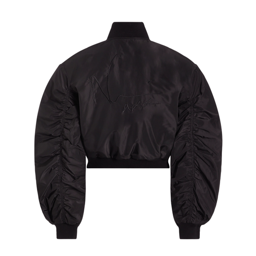 The back of a black bomber jacket set against a white background. It features oversized cocoon sleeves and a black "Naomi" embroidered signature.