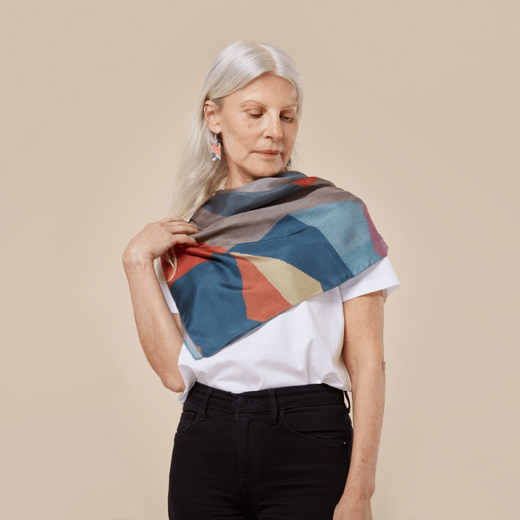 A woman with white straight hair wearing a white t-shirt, black jeans and a blue and red silk scarf.