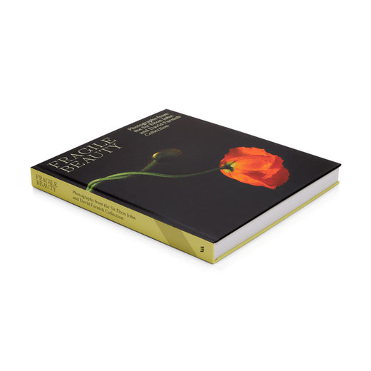 Side view of a hardback book. The cover image features a photograph of a red poppy set against a black background.