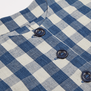 A detail of a blue and white check jacket with brown bottons.