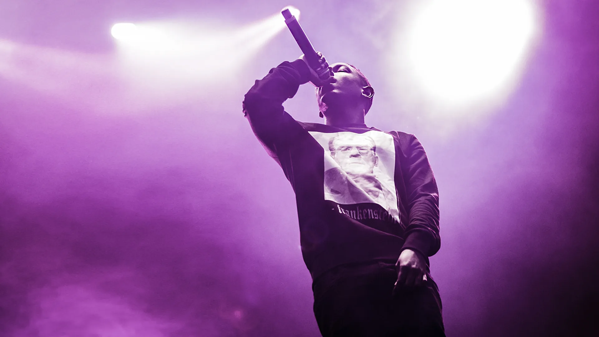 Young Kendrick Lamar rapping into a microphone with purple lights behind him