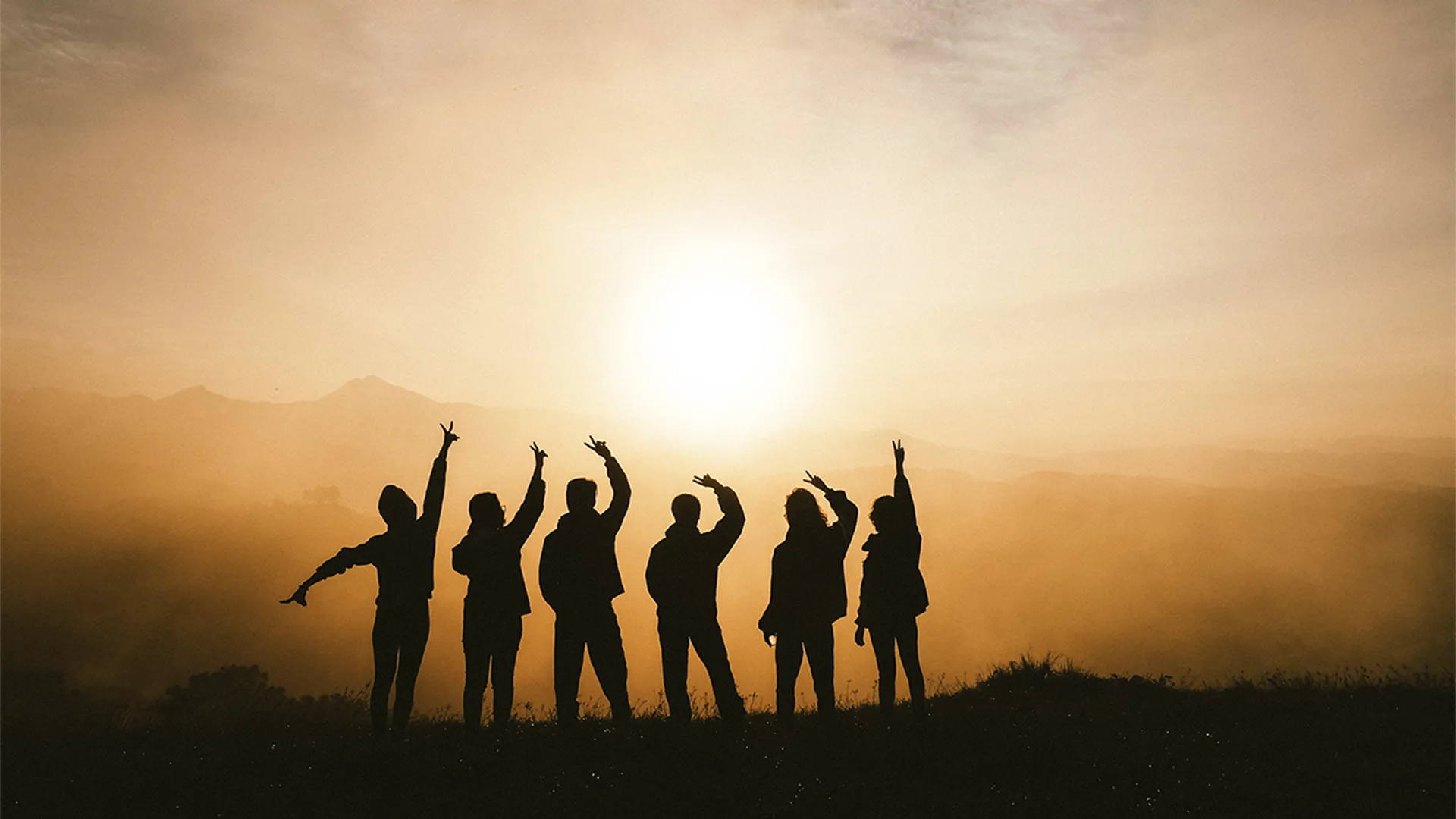 Silhouette of six people on top of a mountain