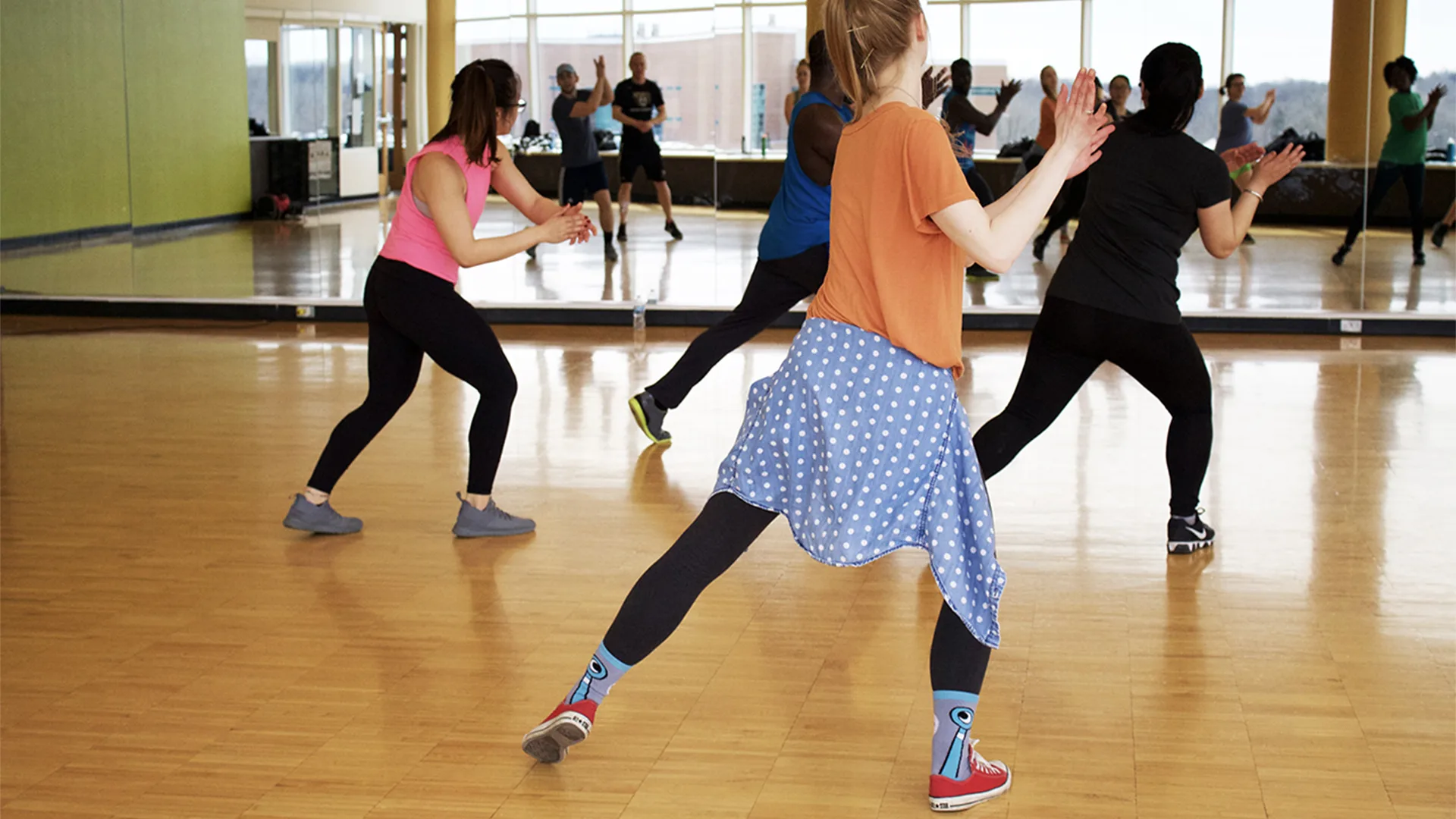 People dancing in dance studio with mirrors in front.