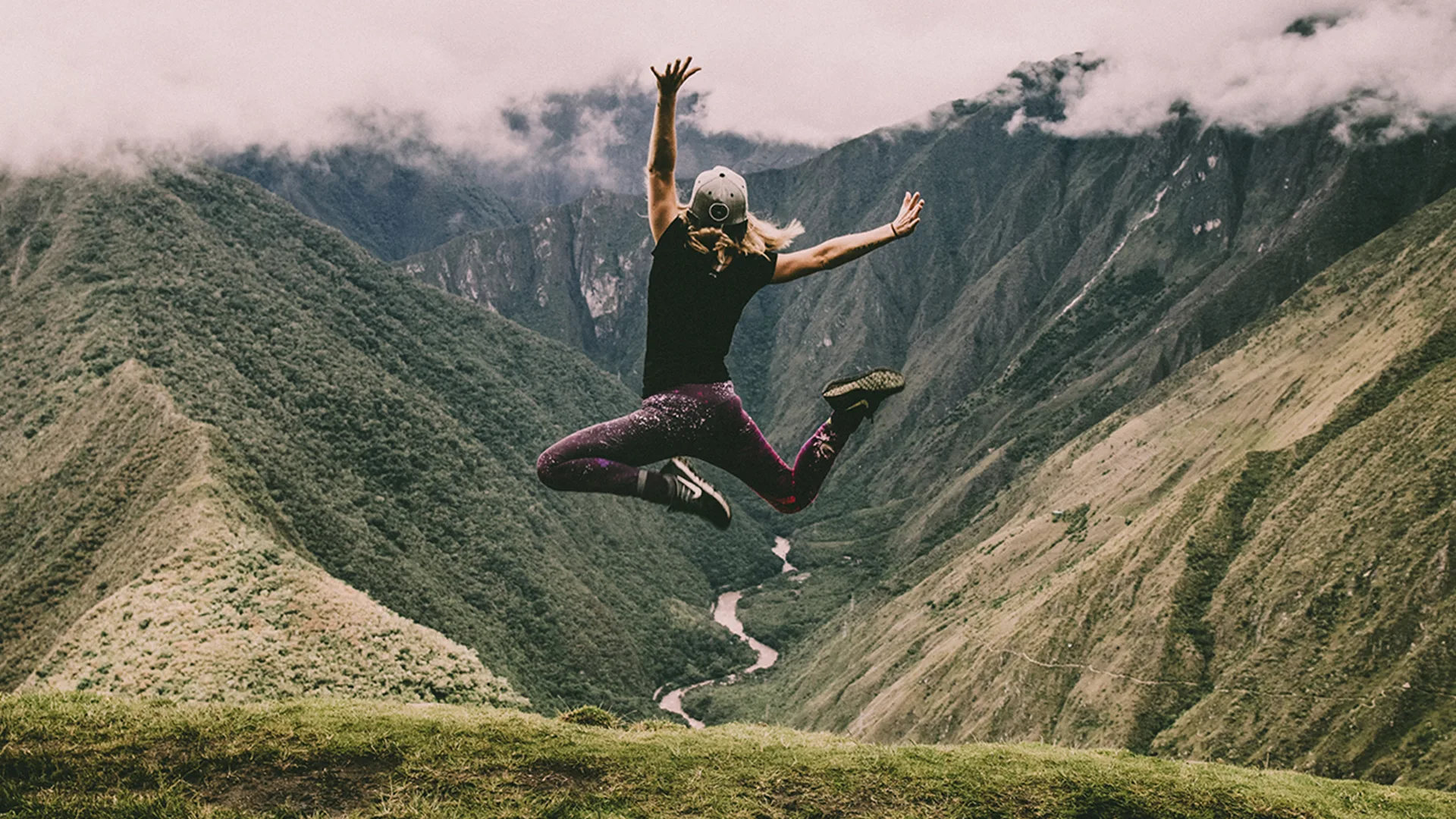 Woman jumping in the air in front of greenery view