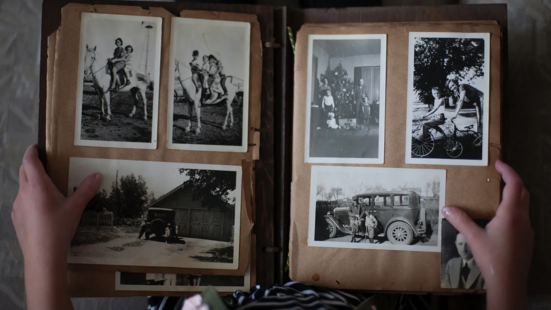 " Person opening photo album displaying grayscale photos