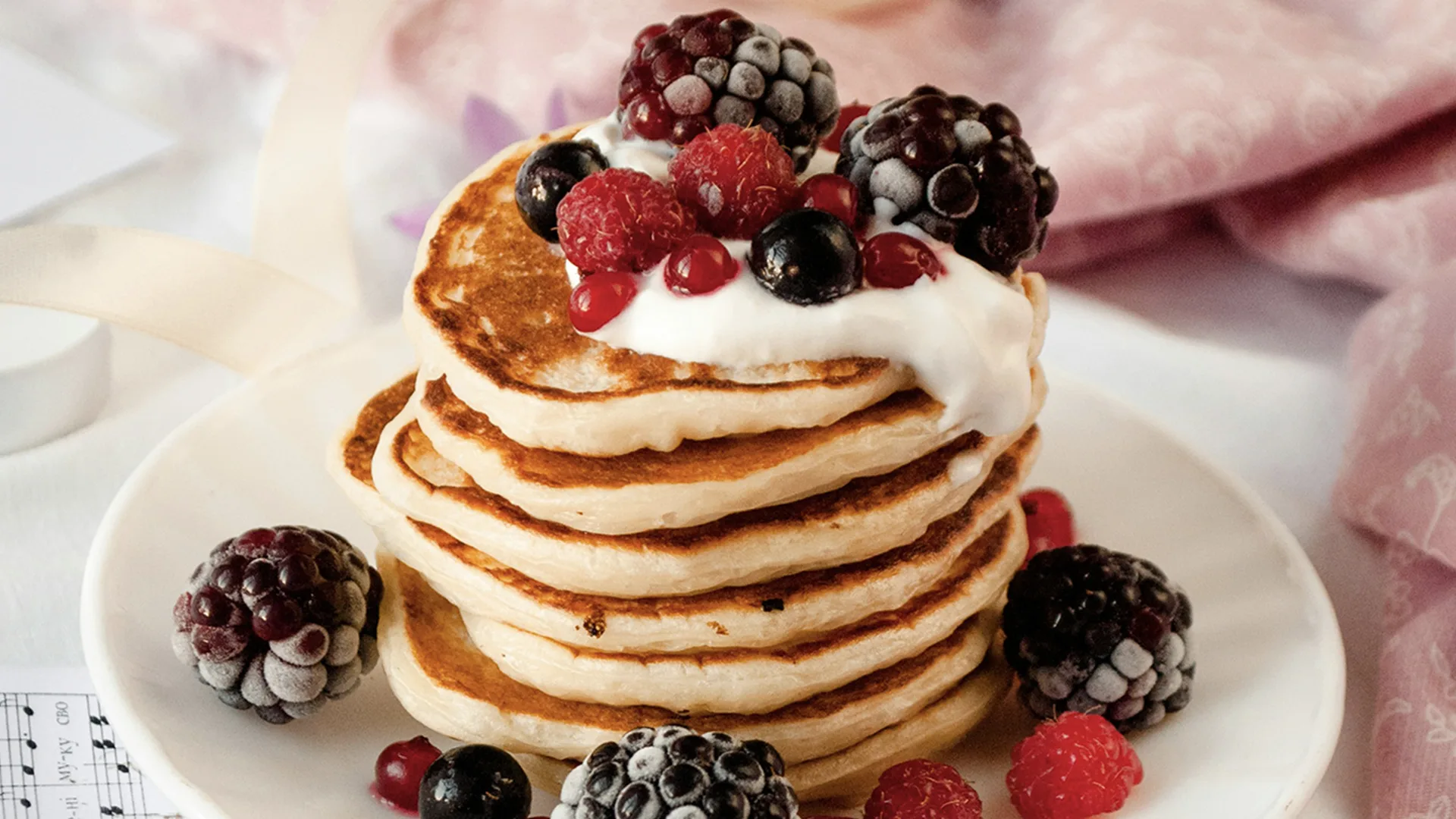 Stack of small pancakes with blackberries and yoghurt