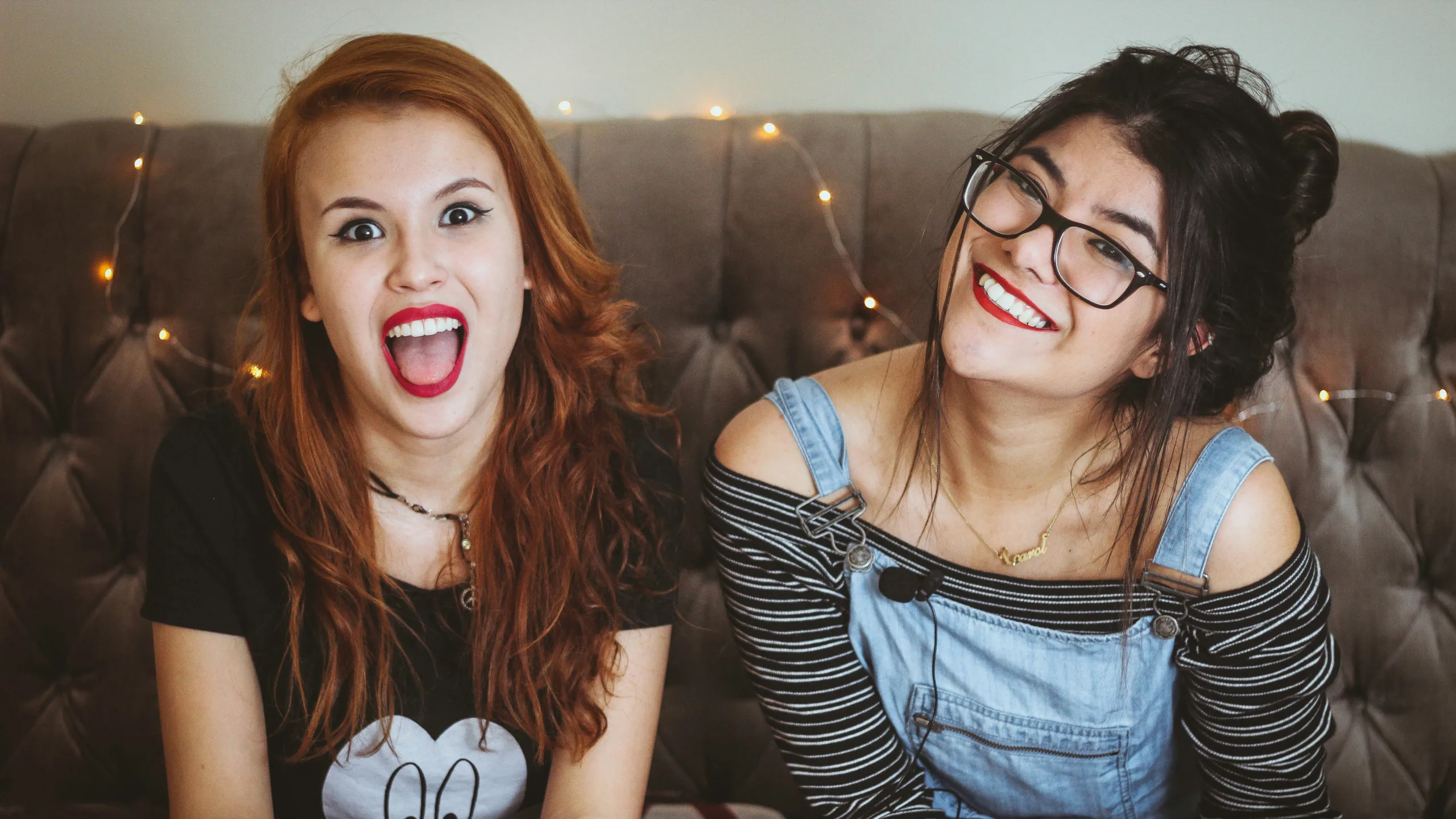 Two young women sat on a sofa laughing