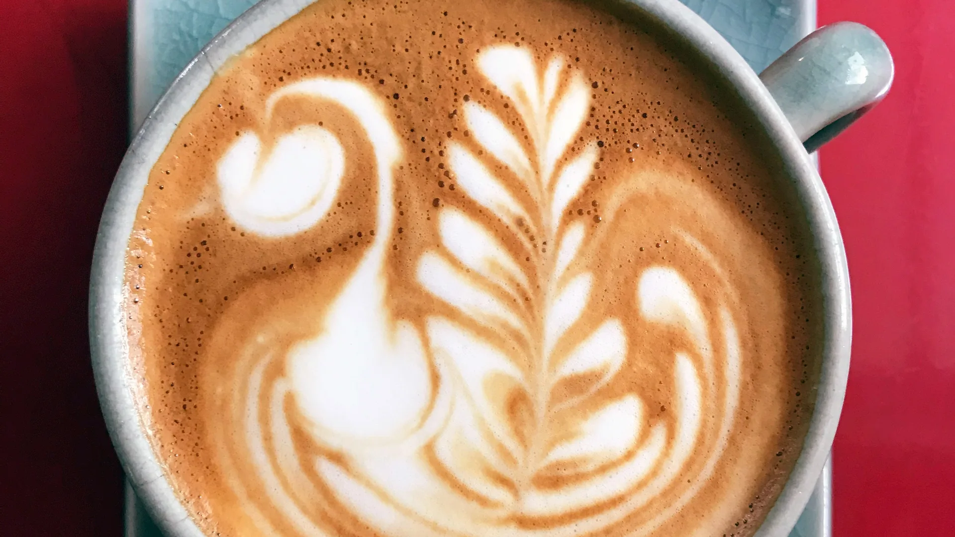 Photograph close up of a coffee with a leaf decoration in the foam