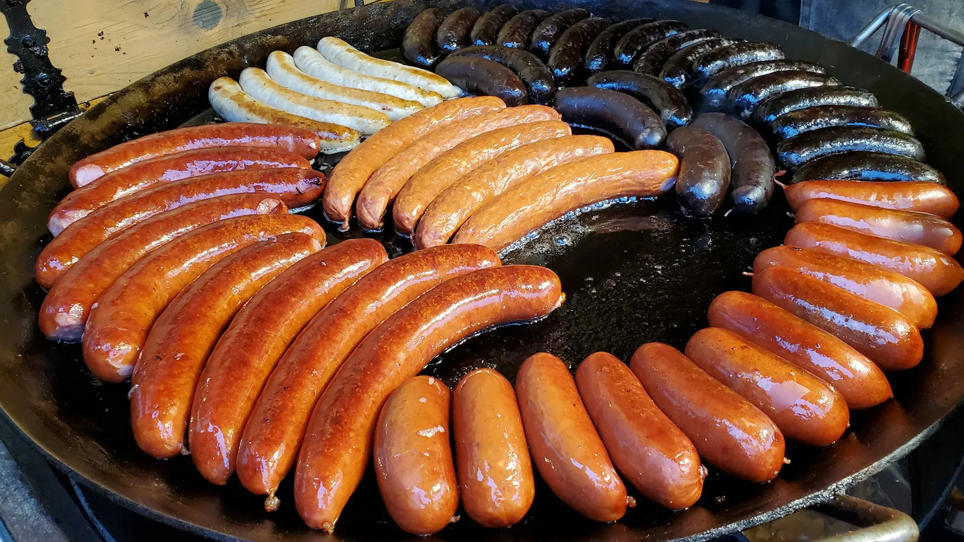 Sausages sizzling on a large round grill