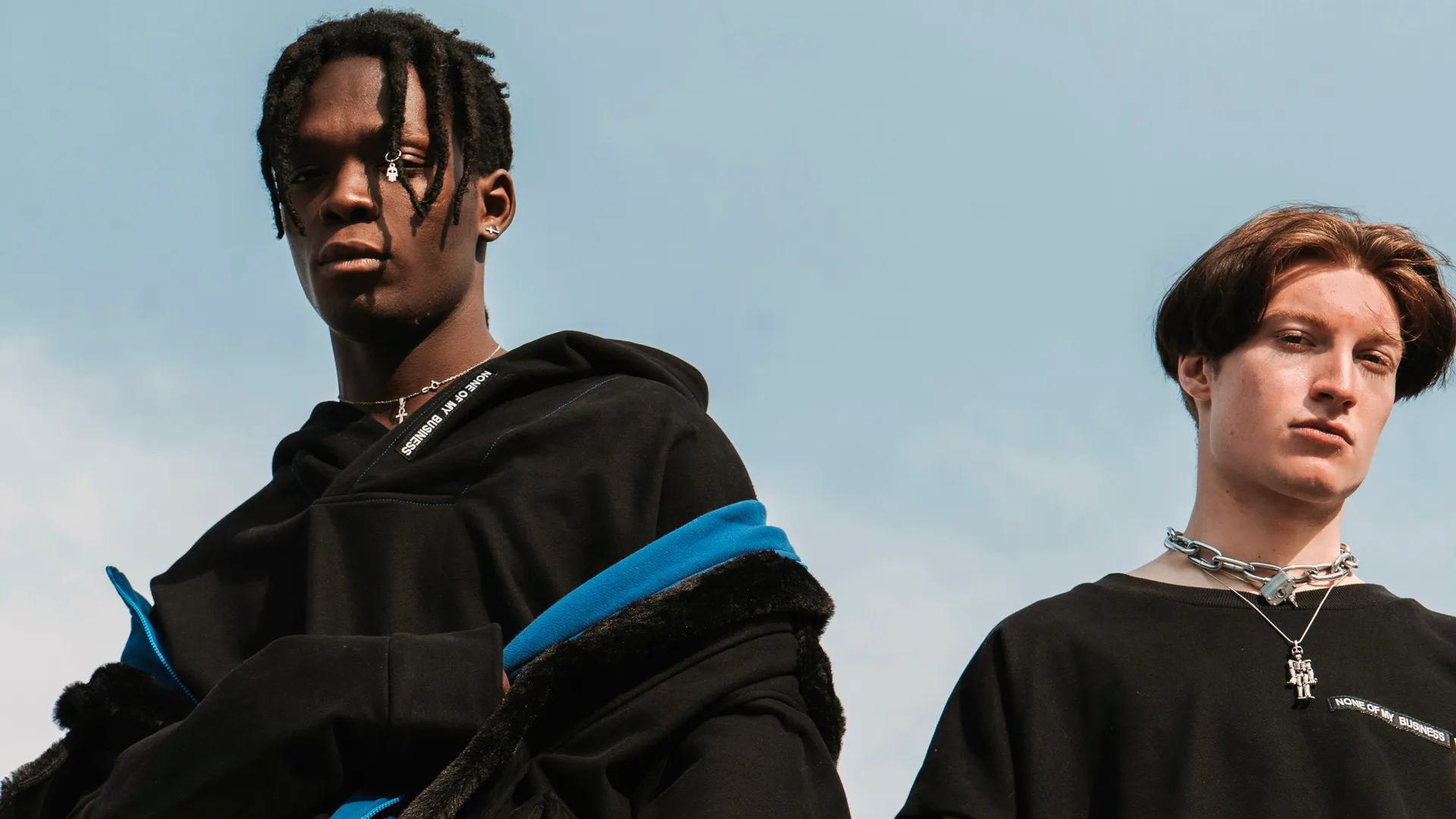 Two men in black jackets pictured in front of the sky