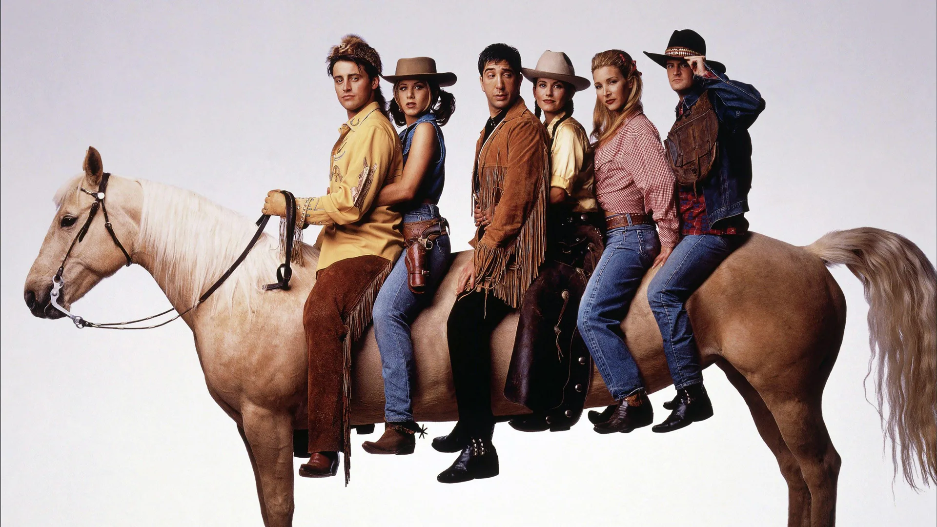 A photo of the cast of the TV show Friends sat on an unusually elongated horse which has been photoshopped - they are wearing western clothing all against a grey background
