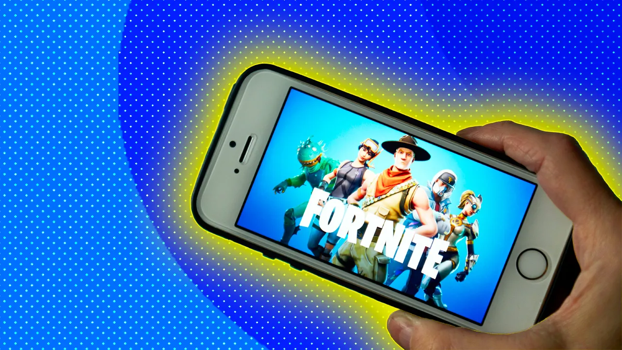 A photo of a hand holding a phone that has FORTNITE on the screen - against a blue dotted background with a yellow halo