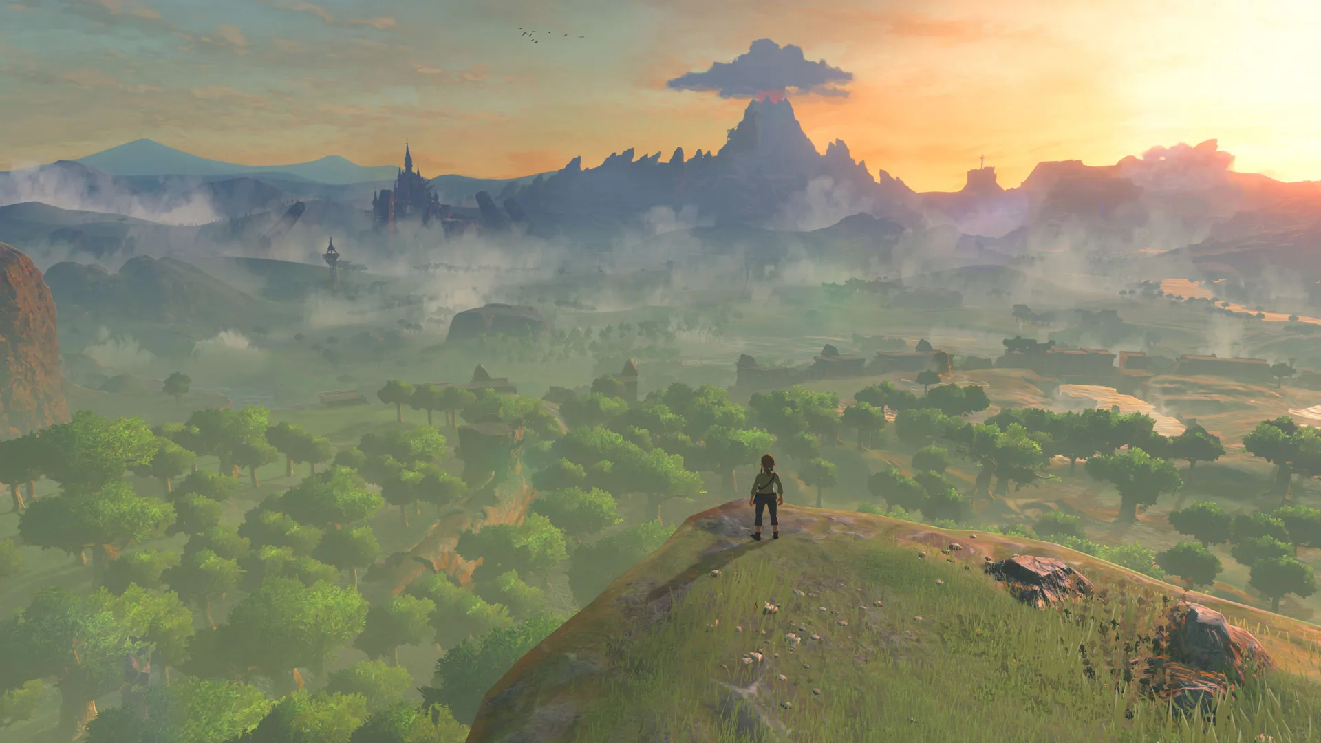 A scene from Zelda: Breath of the Wild showing a vast landscape at dusk with a sunset in the background. Link stands on a hill edge surveying the green landscape where clouds hang low in the distance over the trees.