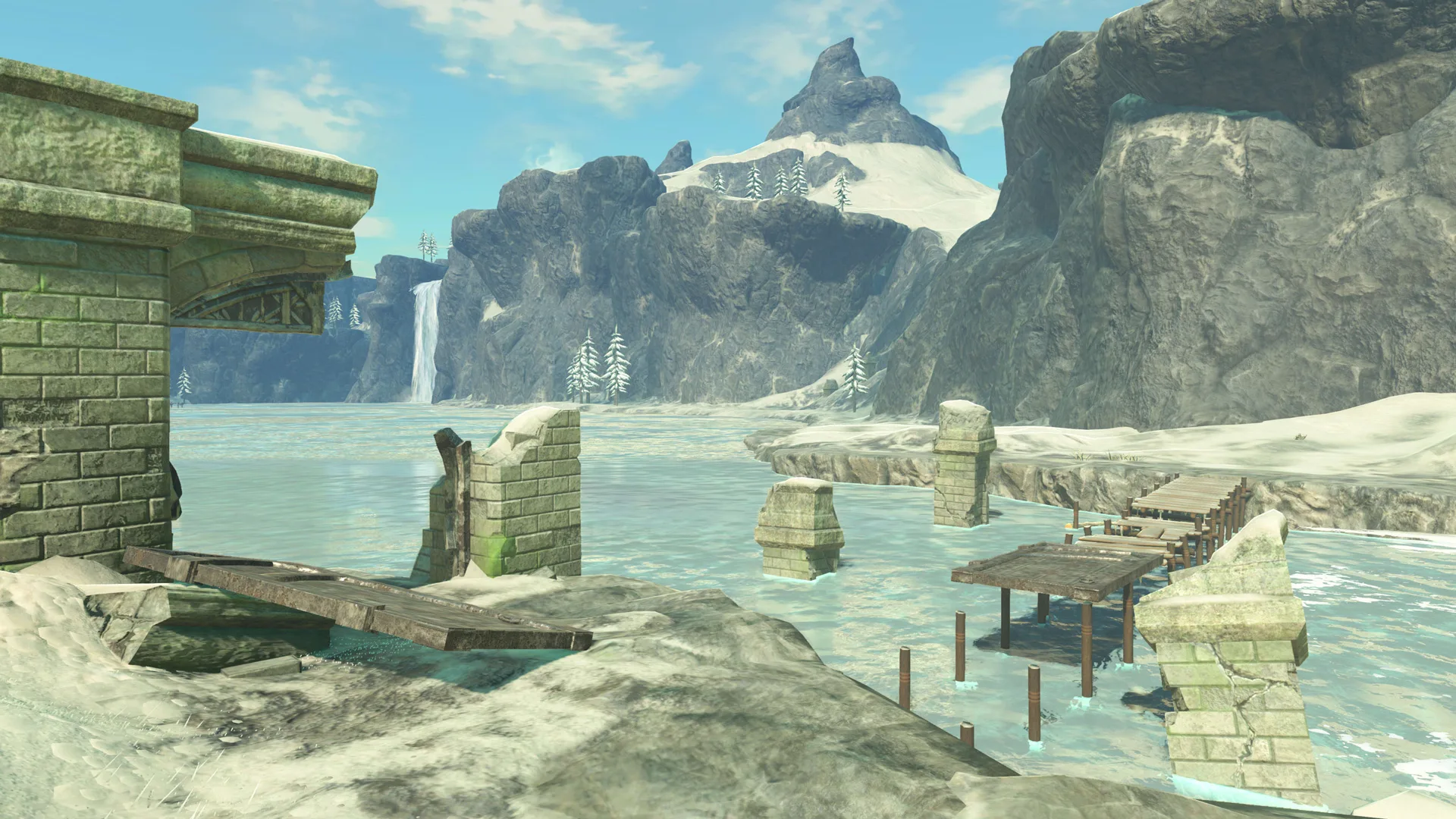 A scene from Zelda Breath of the Wild showing a river scene with rocks and a pier and ruins sticking out of the water. In the distance are snowcapped mountains and blue sky.