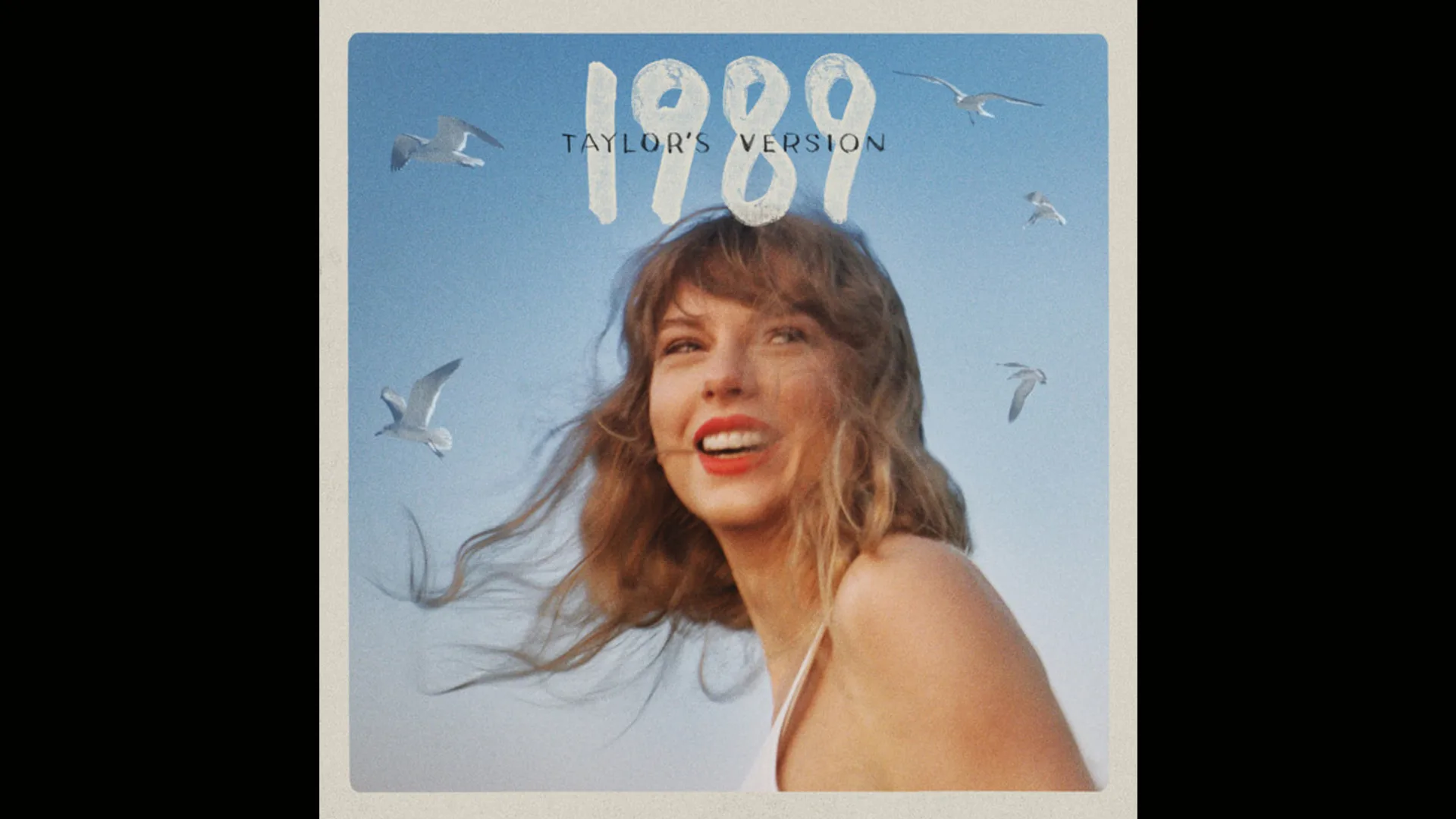 An image of Taylor Swift's album 1989 - Taylor's Version showing the singer laughing with her hair blowing against a blue sky with seagirls circling her.