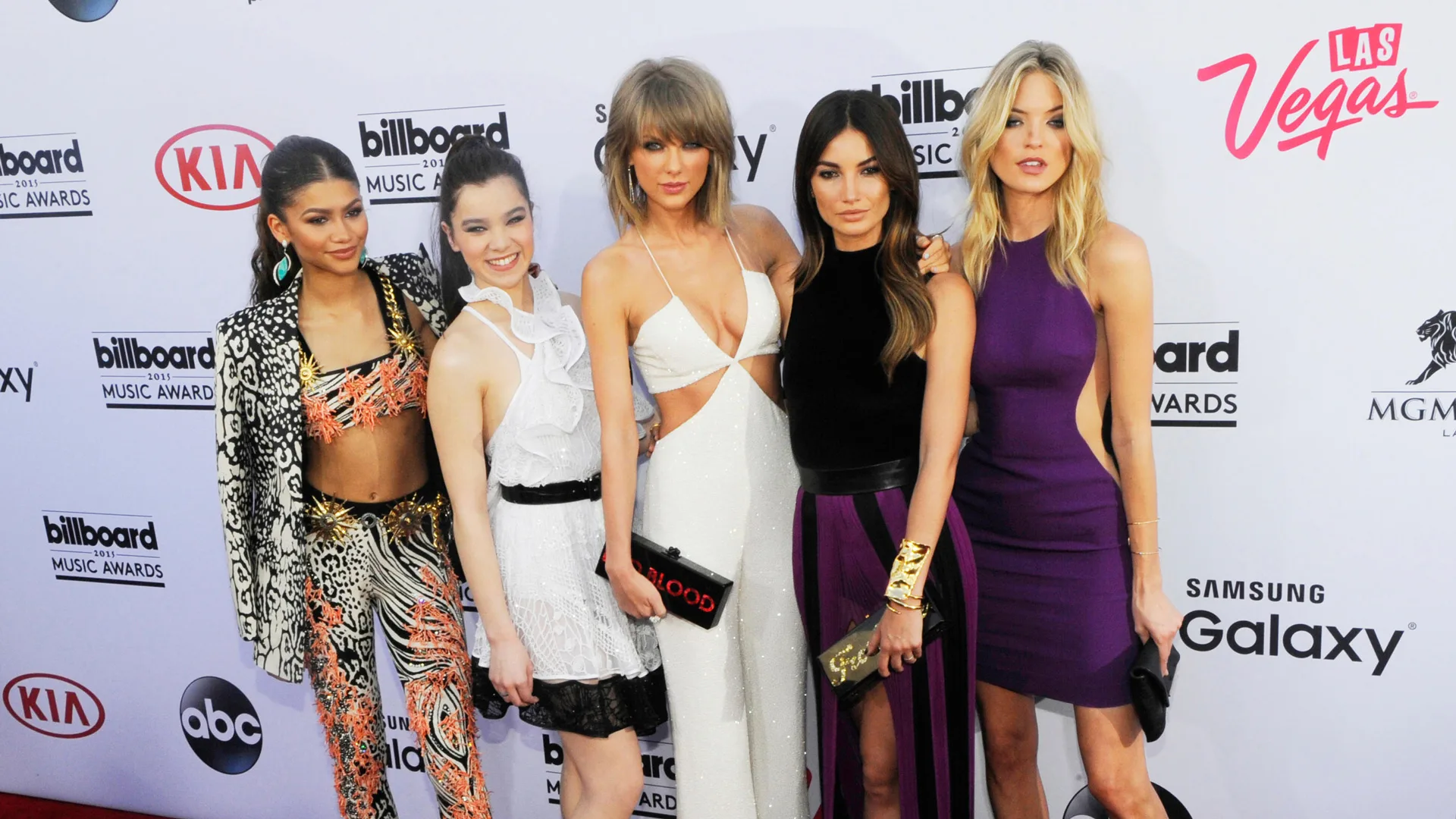 A photograph of Zendaya, Hailee Steinfeld, Taylor Swift, Lily Aldridge and Martha Hunt all stood for a photo on the red carpet against a billboard with brand names.