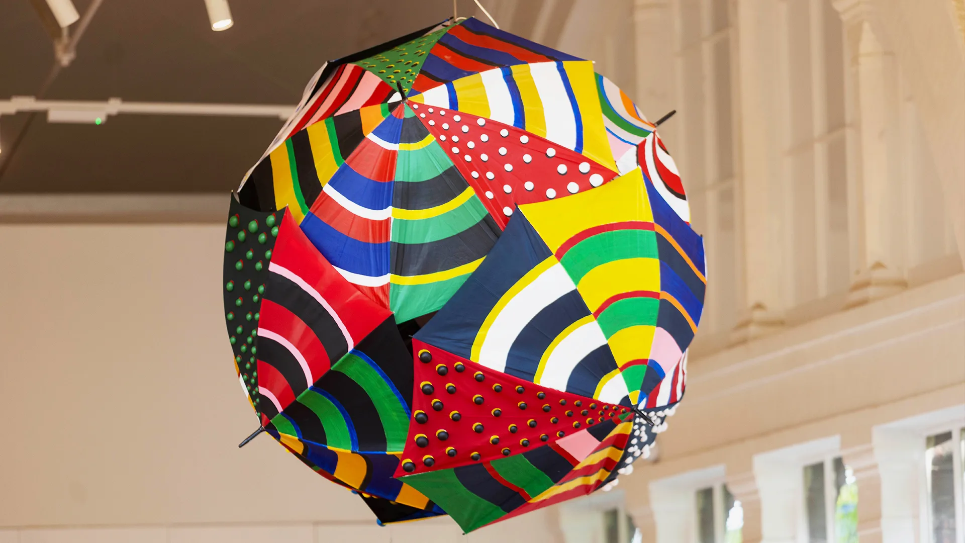 A 3d Yōkai monster is suspended from the ceiling of the Young V&A museum. It is made of multiple umbrellas attached together so it looks like a big colourful ball!