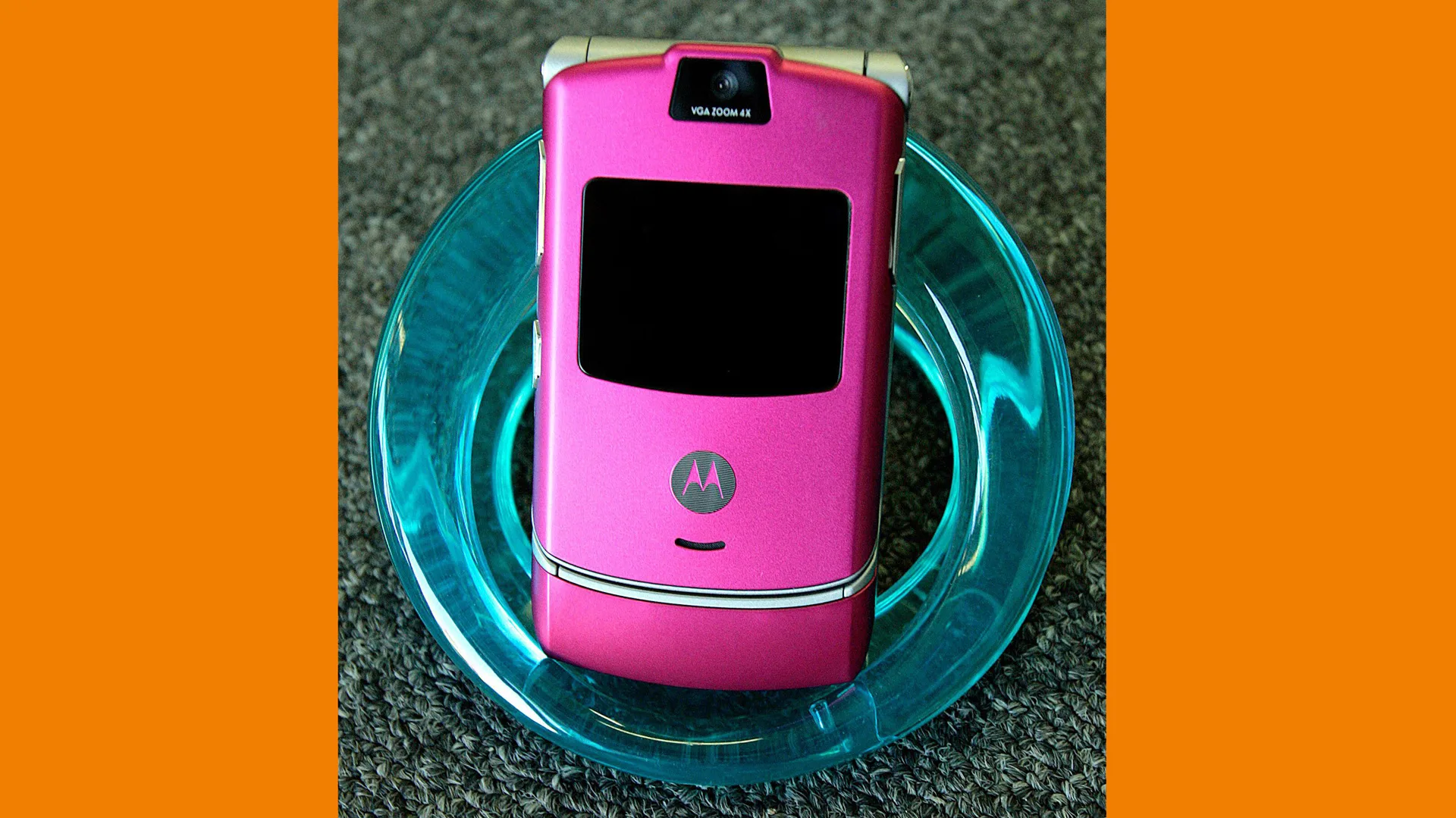 A photograph of a Motorola Razr phone in pink sat in a blue glass bowl with orange borders