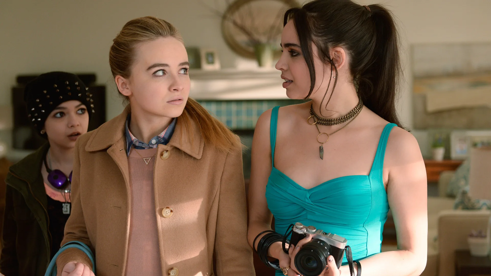 A photo of Sabrina Carpenter and Sofia Carson in a tense discussion. Sofia is wearing a blue top and Sabrina a beige coat.