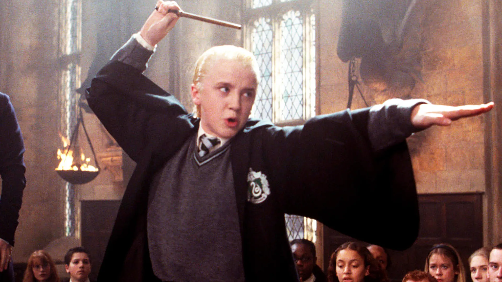 A photograph of Draco Malfoy in Harry Potter holding his wand in a duel pose ready to fight in Snape's classroom