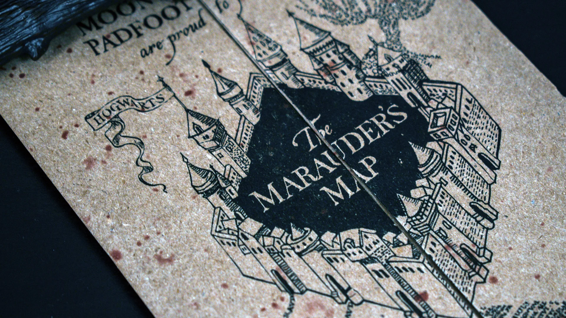 A photo of the Maurader's Map from Harry Potter up close showing the text THE MAURADERS MAP surrounded by black and castle illustration