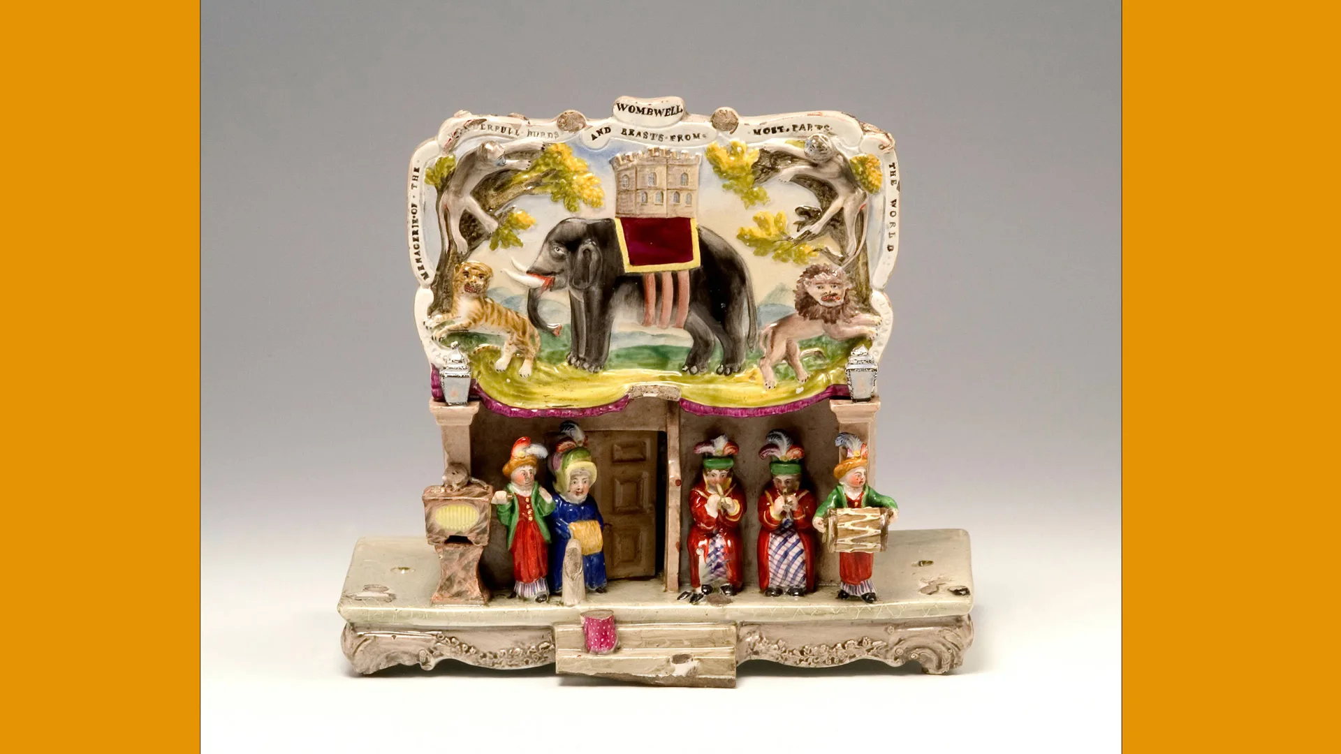 A photograph of a ceramic zoo showing figures and animals such as an elephant in a vertical view with bright greens yellows and reds, collected by Henry Willett