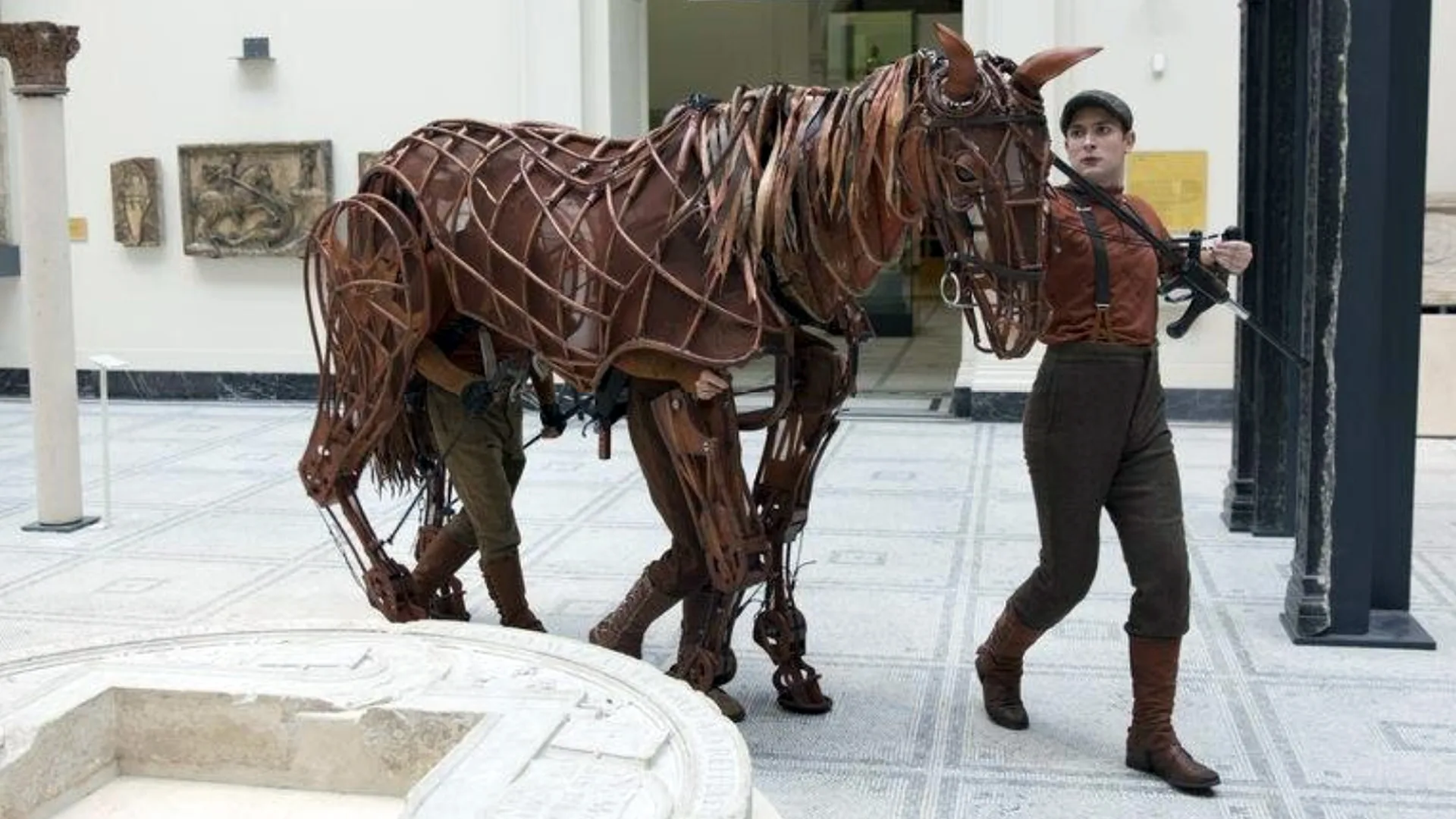 A photo of the horse puppet from War Horse being walked through the Young V&A museum by a puppeteer.