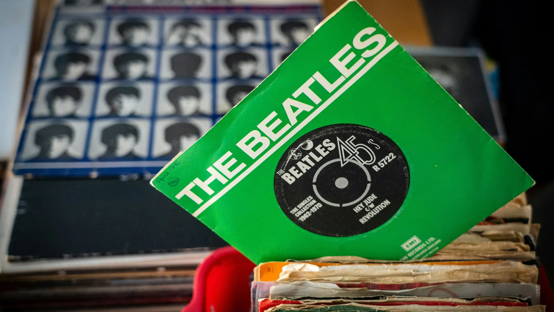 A photo of a Beatles record of Hey Jude in green against the album A Hard Days Night