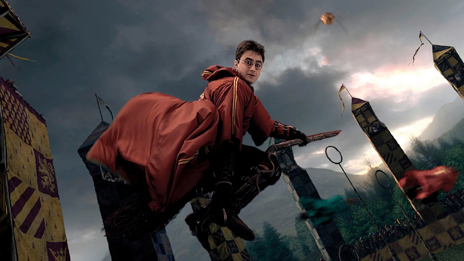 A scene from Harry Potter showing Harry flying on his broom during a Quidditch match with the school in the background and a grey looming sky.