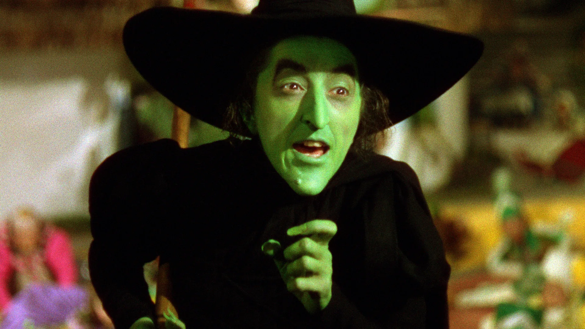 A photo of the Wicked Witch of the West from The Wizard of Oz showing her pointing to someone off camera with an angry expression.