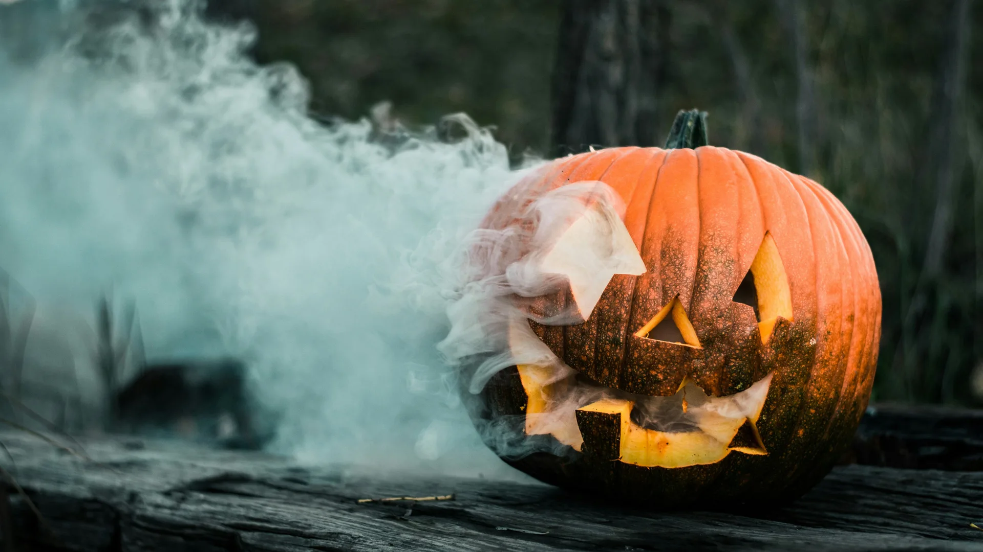 A photo of a pumpkin with a smoking eye against a dark background.