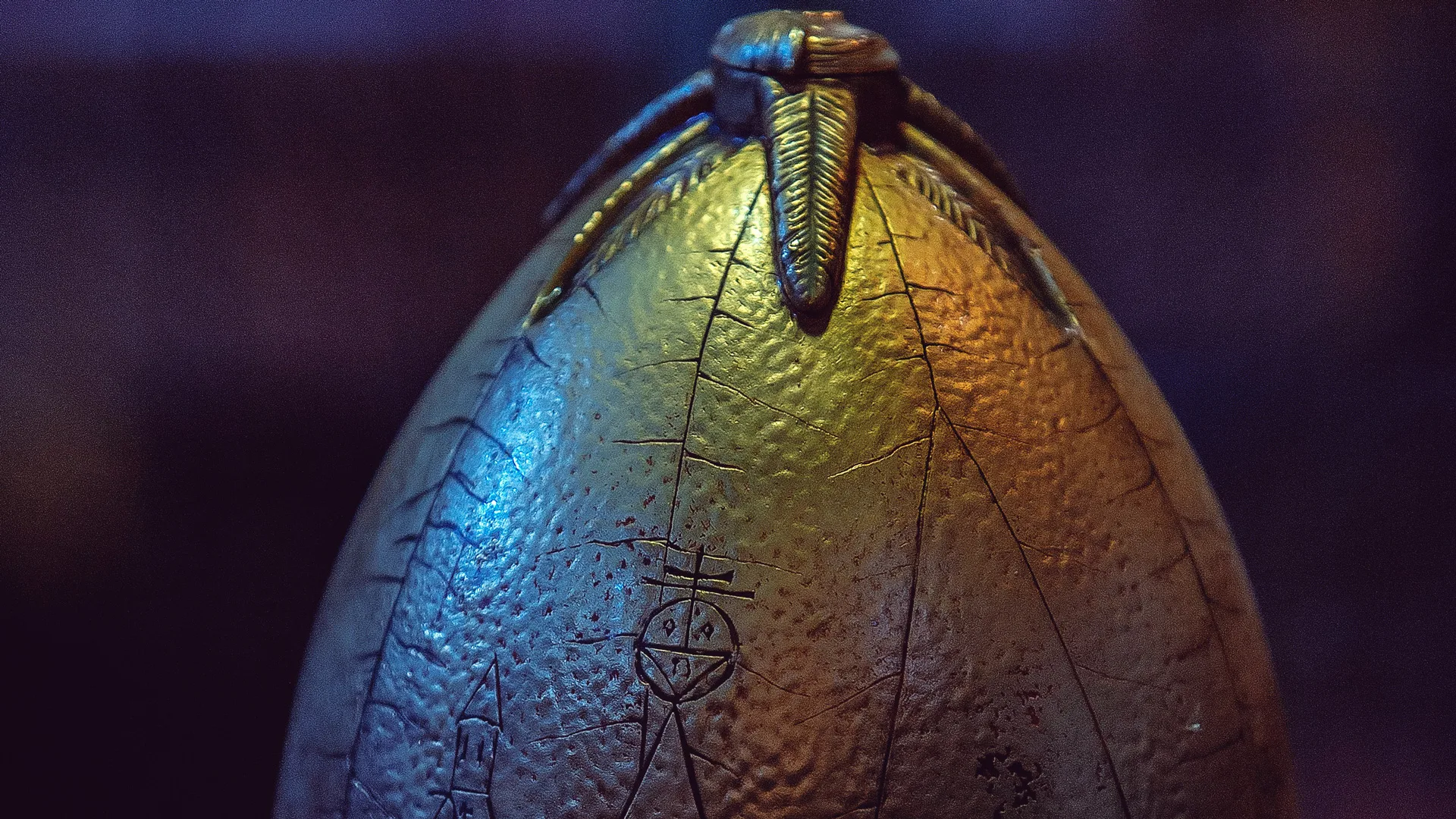 A photo of the egg from Harry Potter that opens to mermaid song. It is shiny and iridescent against a dark background.