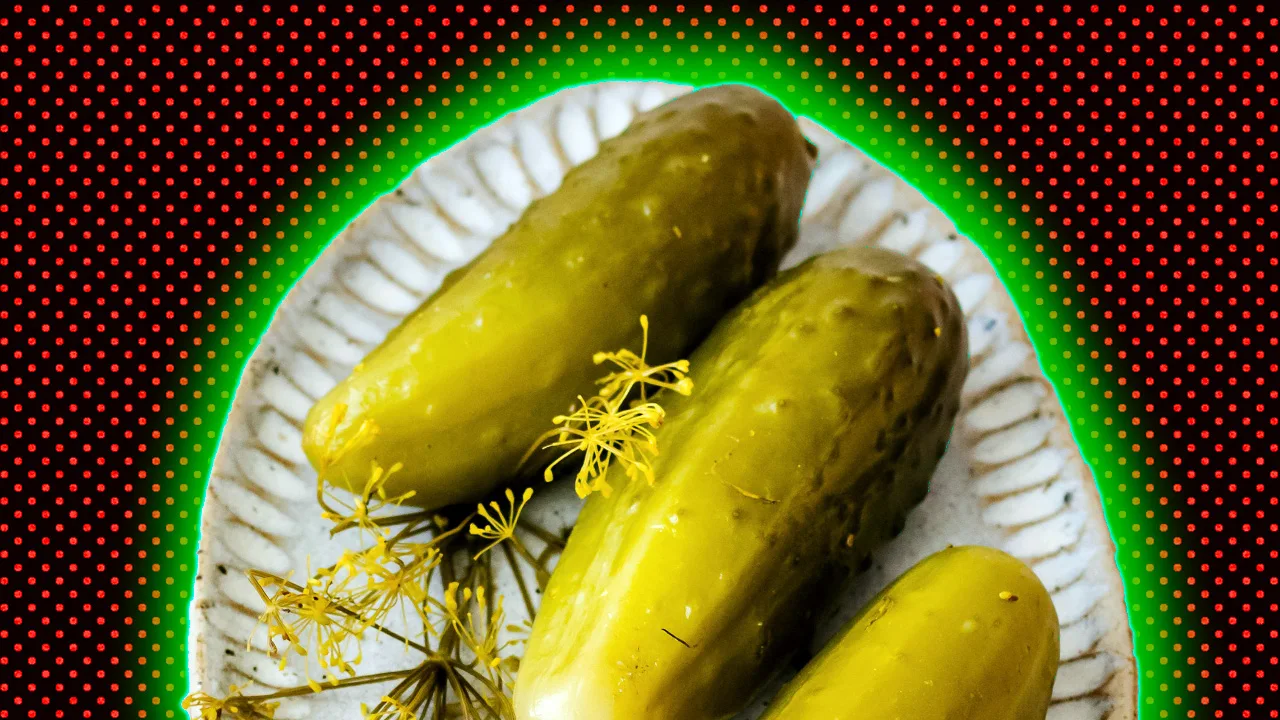 A plate of pickles with yellow garnish against a black and red dotted background with a green halo.