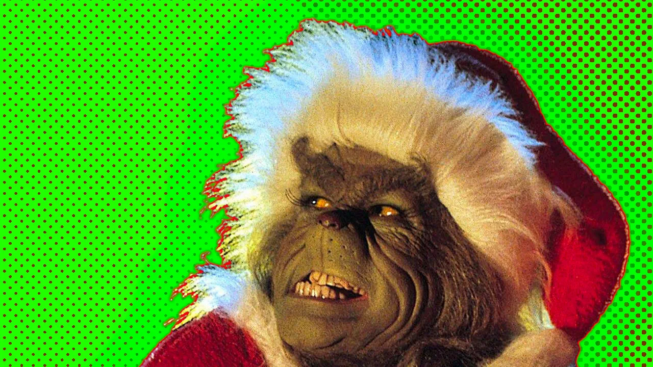 The Grinch grimacing his teeth in a Santa hat with a red halo against a green halo.