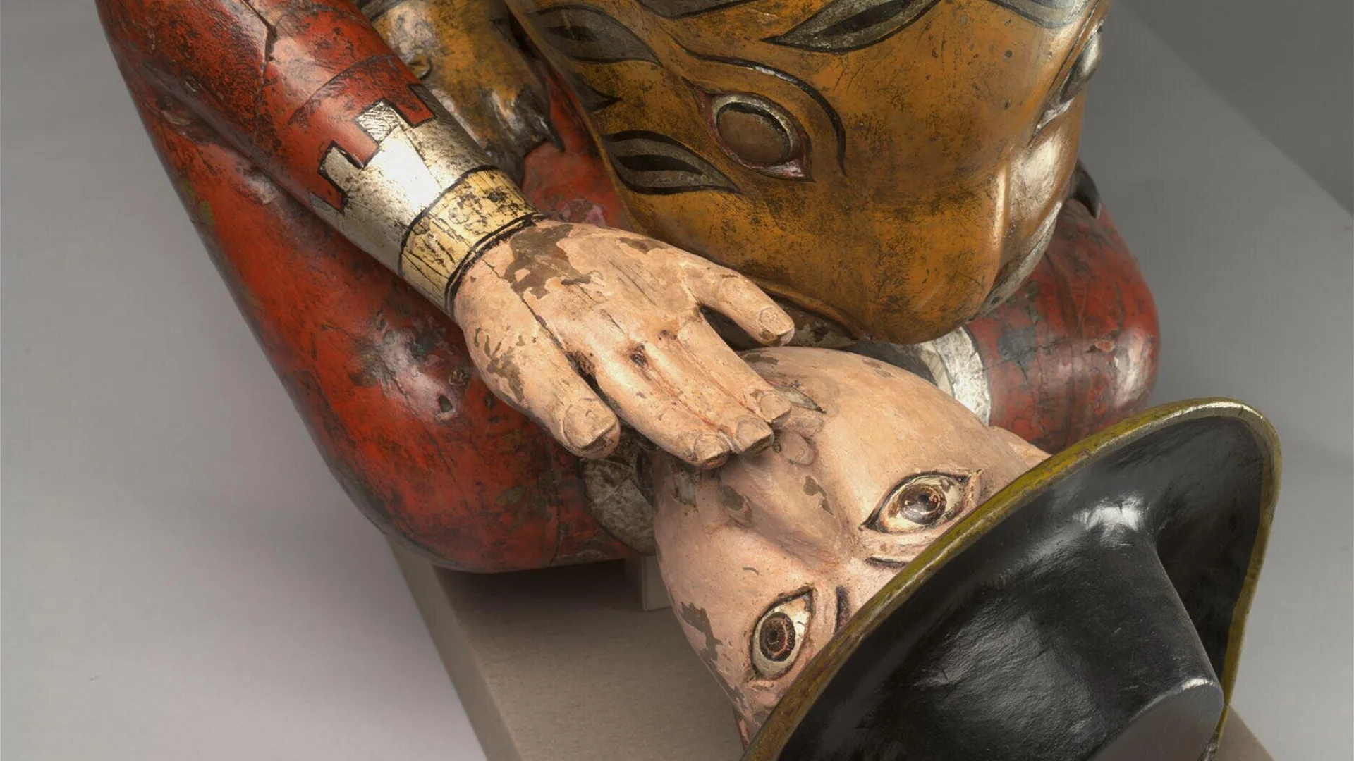 A close up of the V&A object Tippoo's Tiger showing the soldier screaming with a hand over his face. He is wearing a red jacket and black hat.