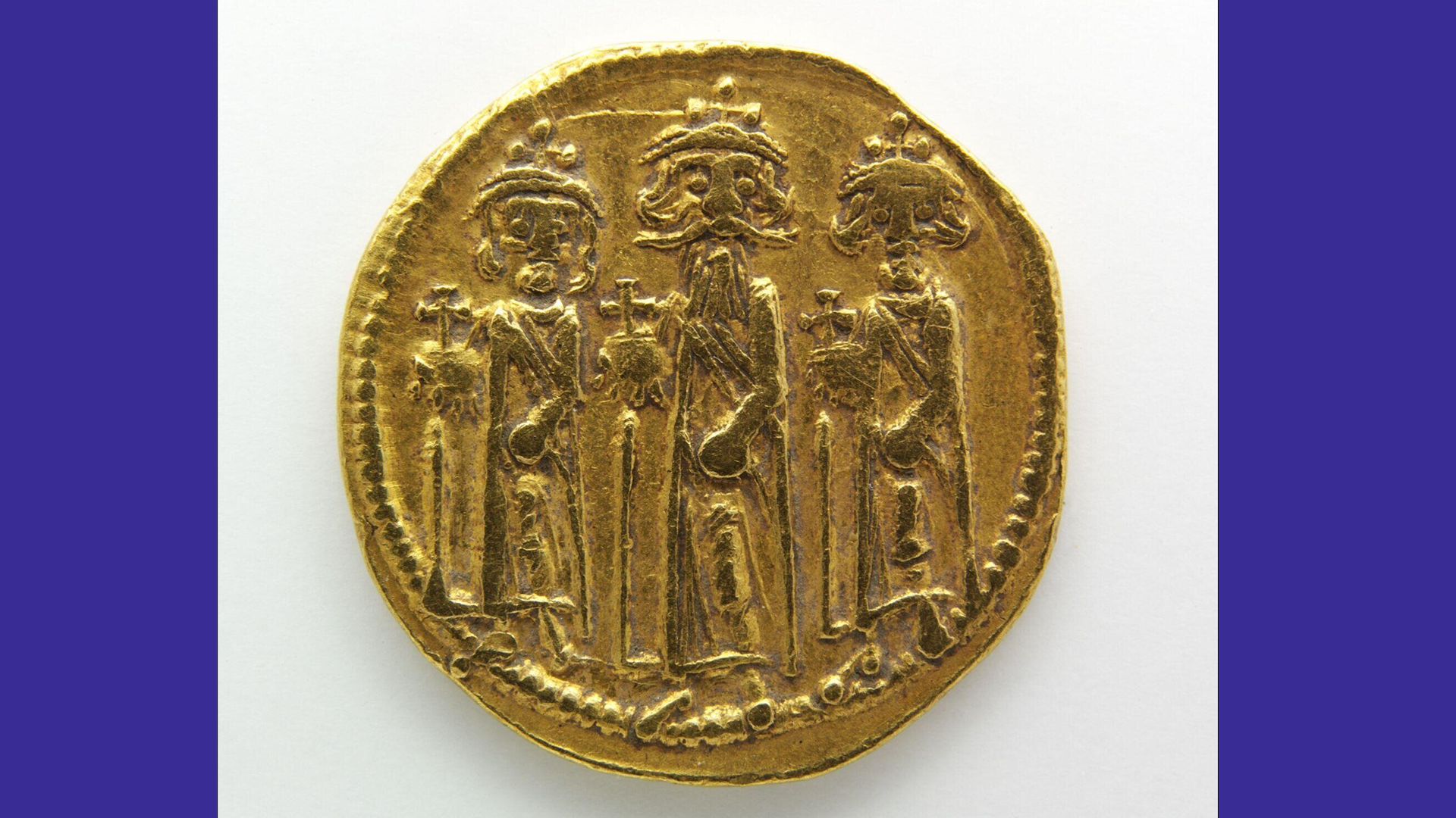 A photo of a gold coin showing three figures engraved in it - it is against a white background with purple borders.