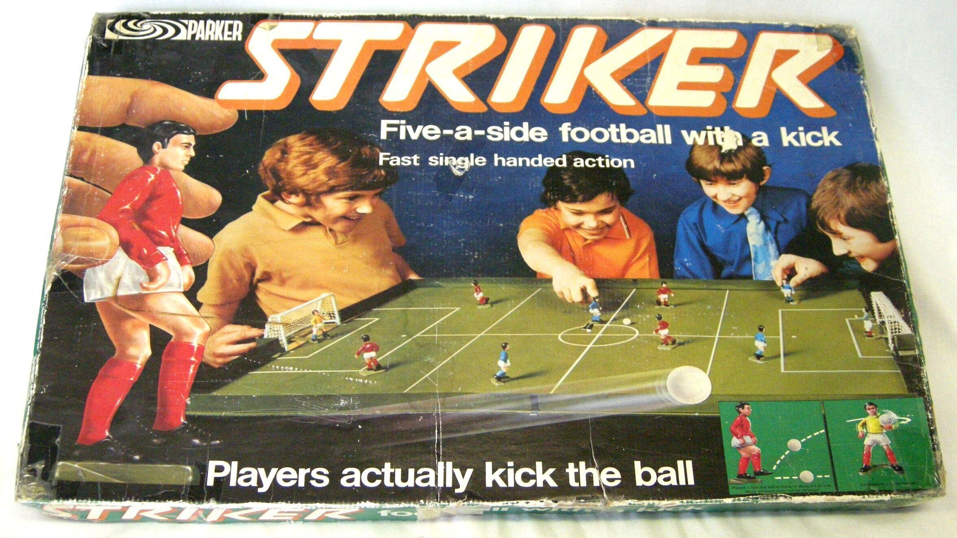 An image of the board game STRIKER showing four children playing the game which is a green football pitch with mini footballers.