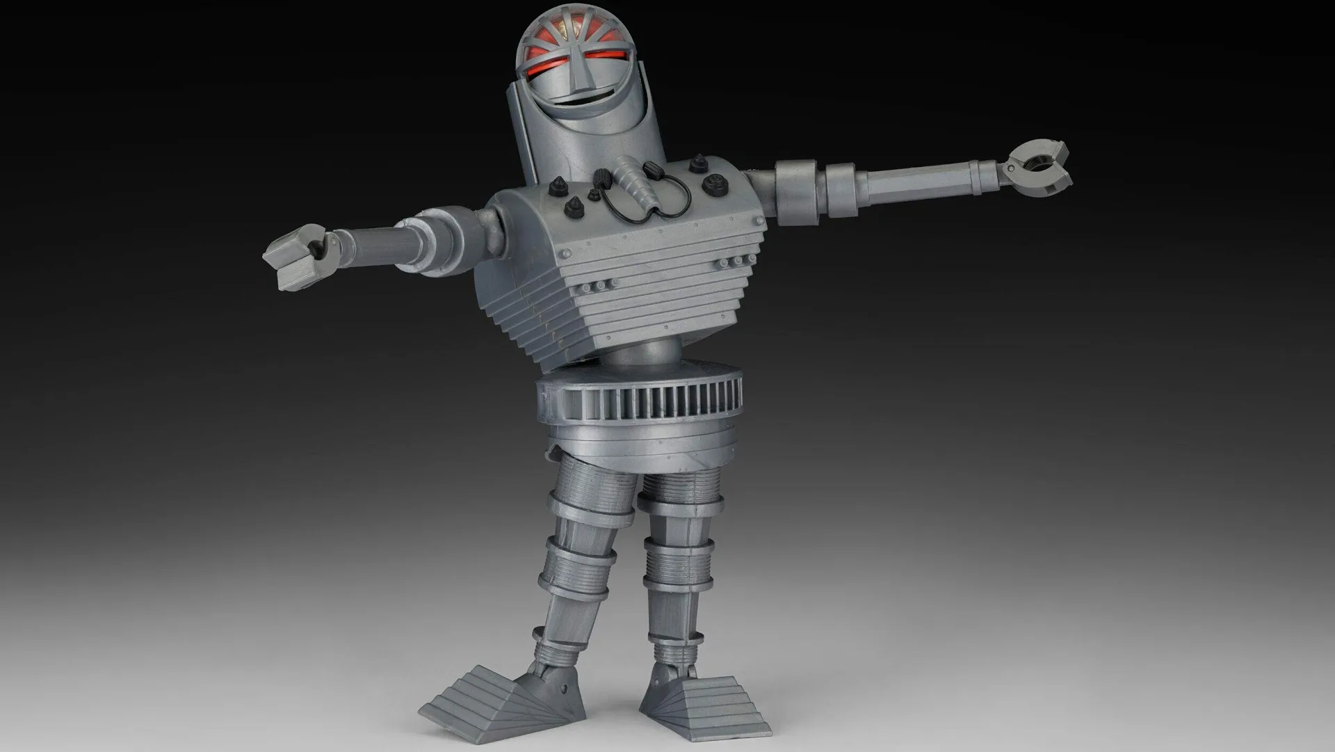 A photo of a silver robot with red eyes, arms stretched out against a grey and black background.