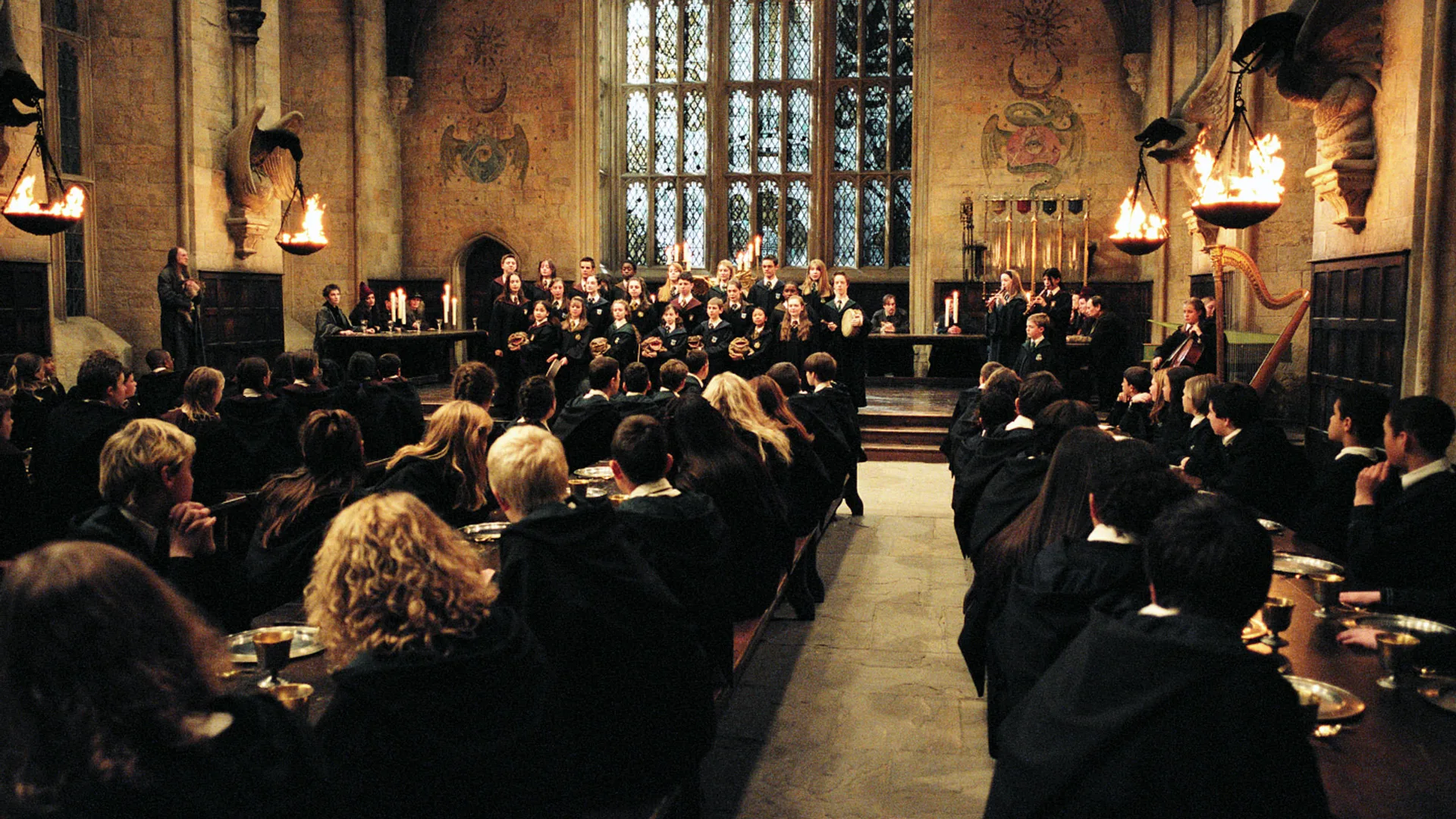 A still from Harry Potter: The Prisoner of Azkahban showing the children in the hall watching a group of other students presumably singing.