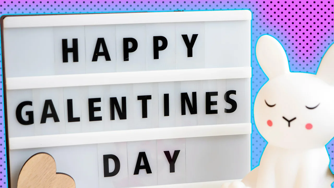 A photo of a sign saying HAPPY GALENTINES DAY in black and white and wooden heart below and a white plastic rabbit with closed eyes next to the sign. They are against a pink dotted background with blue halo.