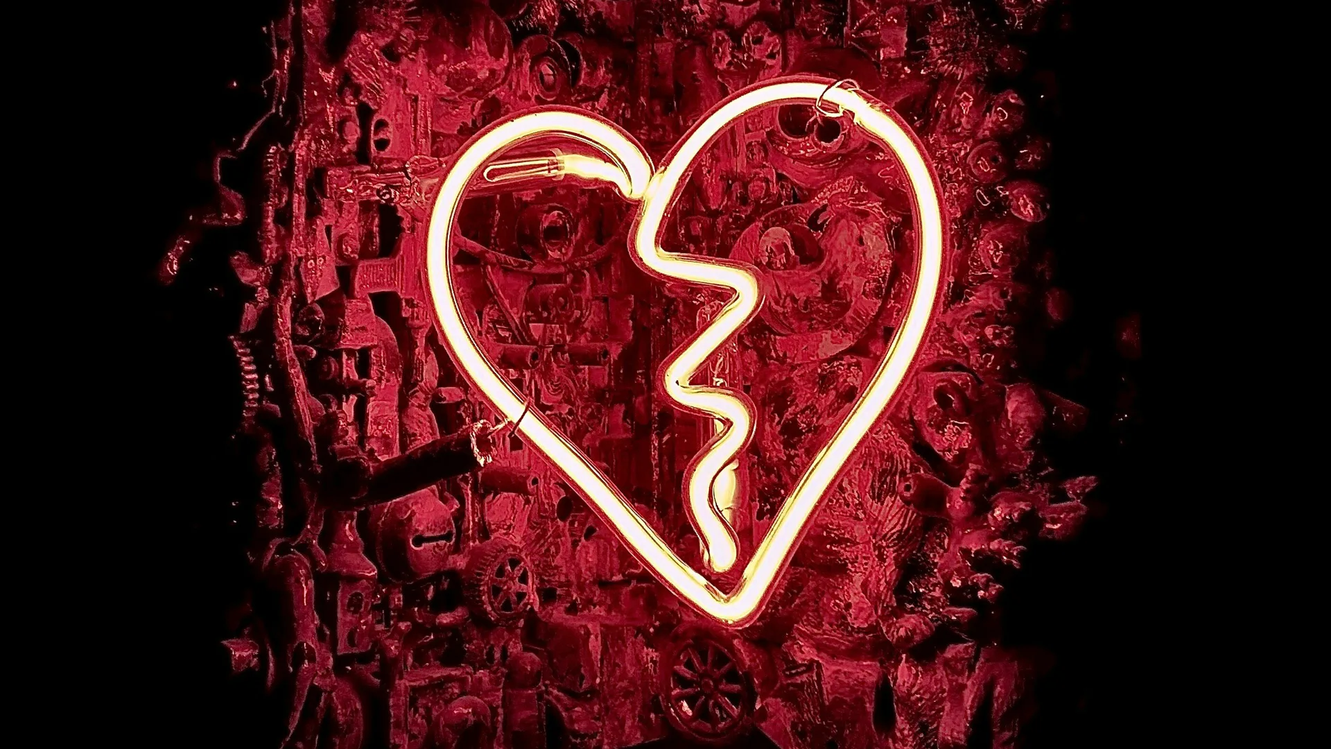 A photo of a neon heartbreak sign in white against a textured red and black background.