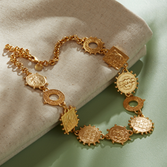 A gold necklace is laid on a green tabletop.