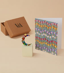 A colourful crescent moon shaped brooch and a floral greeting card.